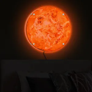 LED planet wall lamp detail showing glowing orange texture surface mounted above a dark bed.