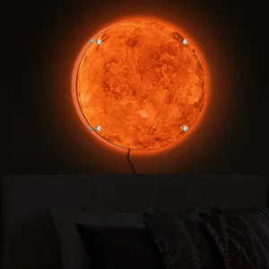 Detail shot of the glowing 3D planet wall lamp casting warm orange light in a dark room.