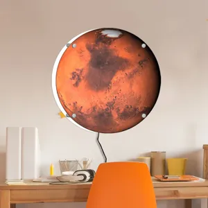 Close-up detail of the glowing Mars wall lamp mounted above a modern wooden desk setup.