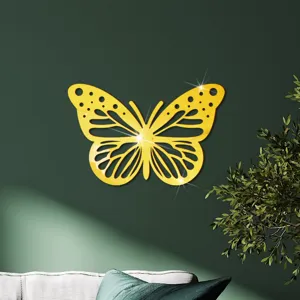 Gedetailleerd uitzicht op de gouden spiegel acryl holle vlinder muursticker op een groene muur.