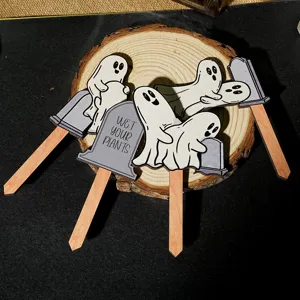 Detail view of funny ghost wooden plant stakes, cute tombstone pot decorations for garden.