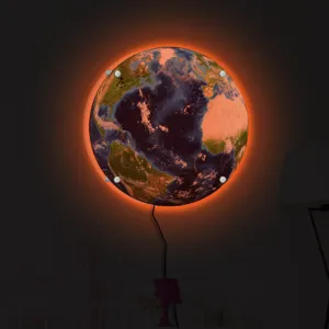 Detailed view of the glowing earth wall lamp emitting warm orange light in a modern dim room.