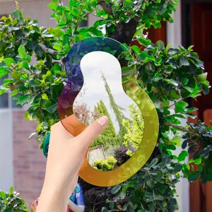 Vue détaillée d'un miroir décoratif en acrylique à dégradé coloré tenu à la main en extérieur.