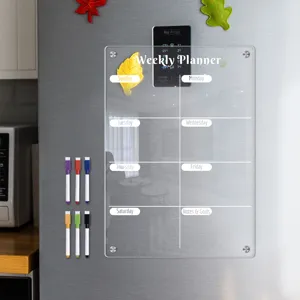Clear acrylic weekly planner board detail showing magnetic mounting and colorful marker pens on fridge.