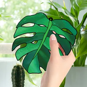Closeup of green monstera leaf acrylic window hanging suncatcher pendant for home decor.