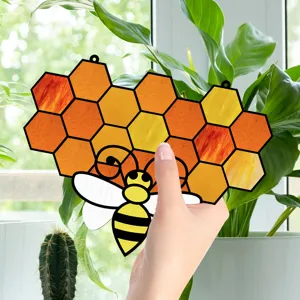 Close-up detail of a colorful honeycomb and bee stained glass hanging window ornament.