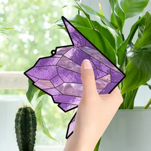 Close-up of a purple geometric acrylic bird hanging ornament displayed near green plants.