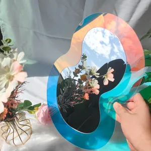 Vue détaillée du miroir mural en acrylique irrégulier iridescent reflétant le ciel.