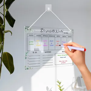 Clear acrylic weekly planner board hanging on the wall with green leaf border design detail.