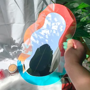 Gros plan d'un miroir décoratif en acrylique au design irrégulier et dégradé reflétant les plantes.