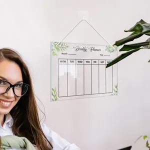 Clear acrylic weekly planner board detail view with hanging rope and green leaf decor.