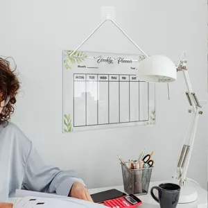 Clear acrylic weekly planner board with hanging string and modern green leaf design