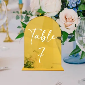 Detailed view of gold acrylic arch table number sign with stand for wedding decor events.