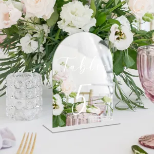 Clear acrylic arch table number sign with white text and base for wedding party decor.