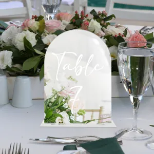 Clear acrylic arched table sign with white text, ideal for wedding table decor and party display.