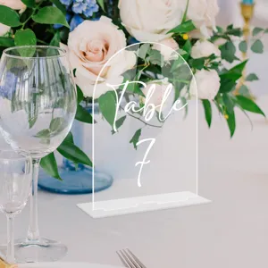 Clear acrylic arched table sign with white base, elegant wedding table number display piece.