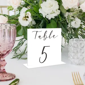 Vista detallada del cartel de numero de mesa de boda de acrilico blanco con texto escrito 5.