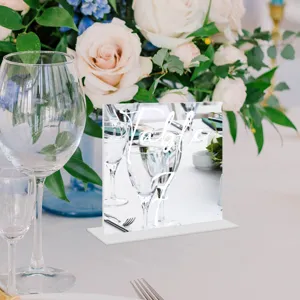 Detalle de tarjeta de número de mesa de boda de acrílico con tipografía blanca y flores.