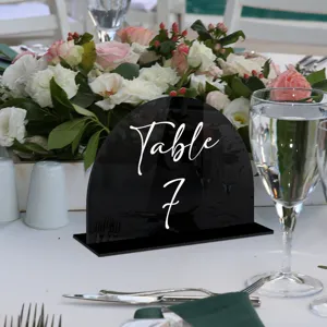 Vista detallada del letrero de mesa de acrílico negro arqueado con letras blancas para decoración.