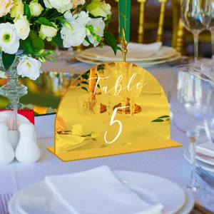 Detalle de número de mesa de acrílico dorado en arco, perfecto para decoración de bodas.