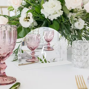 Vista detallada de un número de mesa de acrílico arqueado con decoración floral elegante.