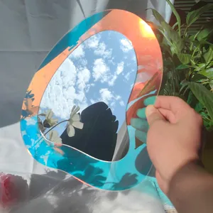 Vue de détail du miroir acrylique irisé irrégulier reflétant le ciel et de jolies fleurs.