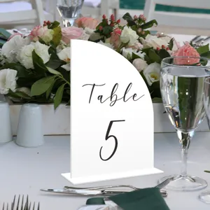 Vista detallada del letrero de mesa de acrílico blanco decorado para bodas y eventos especiales.