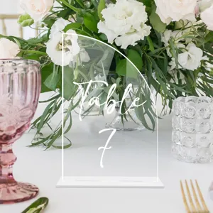 Primer plano del letrero de mesa de boda en acrílico transparente con escritura elegante.