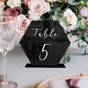 Toma de detalle de un número de mesa de boda acrílico negro hexagonal con elegante decorado floral.