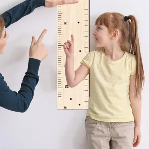 Detalle de medidor de altura de madera para niños con números de escala y estrellas.