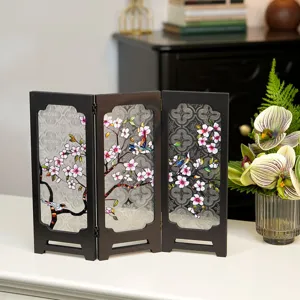 Detail shot of vintage style tabletop folding screen with floral and bird relief glass panel decor.