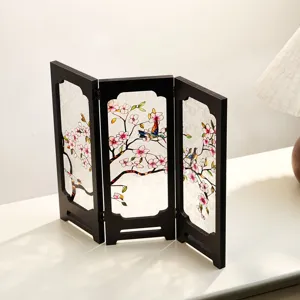 Detailed close-up of a miniature vintage wooden folding screen with floral and bird painted glass.
