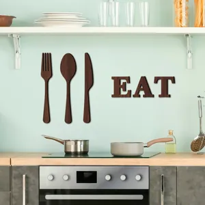 Détail de décoration murale cuisine en bois montrant fourchette cuillère et EAT lettres.