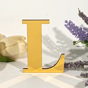 Detailopname van de gele 3D acryl houten letter L in een decoratieve bloemenopstelling.