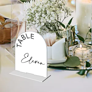 Detail shot of clear arch acrylic wedding table number card with elegant black text display setup.