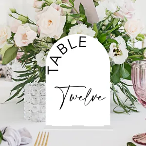 White arched acrylic wedding table number sign with modern black typography for event decor detail