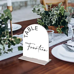 Detail view of white acrylic arch table number sign with elegant black typography for wedding decor.