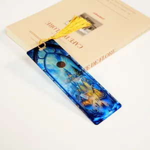 Translucent acrylic bookmark with gold tassel, fantasy winter village illustration for reading.