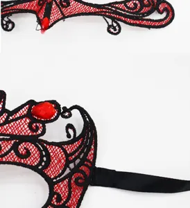 Nahaufnahme Detailansicht einer rot-schwarzen Spitzenmaske mit roten Schmucksteinen.