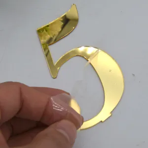 Gold mirror acrylic table number 5 detail shot showing the protective film being peeled off.
