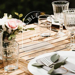 Clear acrylic arched table number sign with white text for elegant wedding decor details.