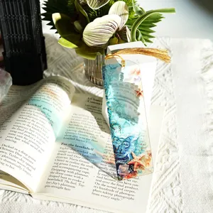 Translucent acrylic bookmark with golden tassel, ocean watercolor design, clear reading accessory.