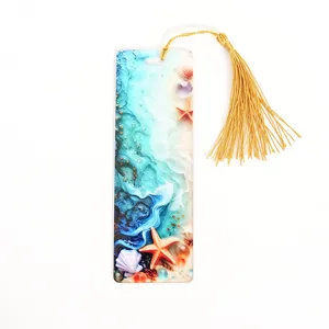 Acrylic bookmark with golden tassel, translucent ocean beach design, elegant reading accessory.