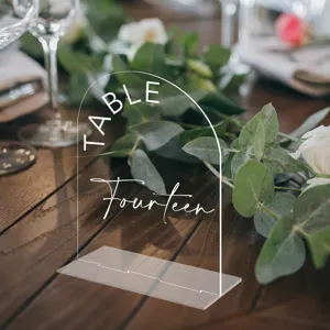 Clear acrylic arch wedding table number sign detail view with elegant base and white text.