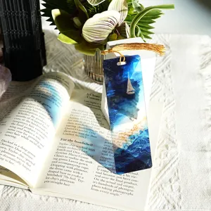 Transparent acrylic bookmark with gold tassel, creative ocean sailboat design for reading.