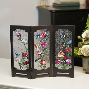 Detailed close-up view of vintage tabletop folding screen with floral and hummingbird pattern.
