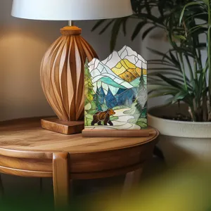Detailed view of stained glass style mountain and bear acrylic ornament on a cozy wooden table.