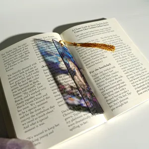 Creative colorful light transmitting acrylic bookmark with golden tassel on open book detail shot.