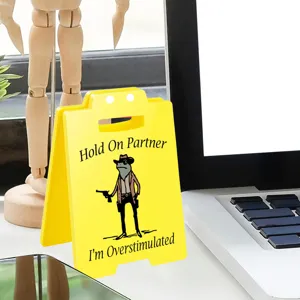 Acrylic desk decor detail view featuring funny cowboy frog design on yellow sign for office.