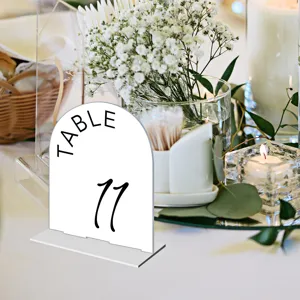 Detailed view of clear acrylic arch table number sign with elegant black typography setup.